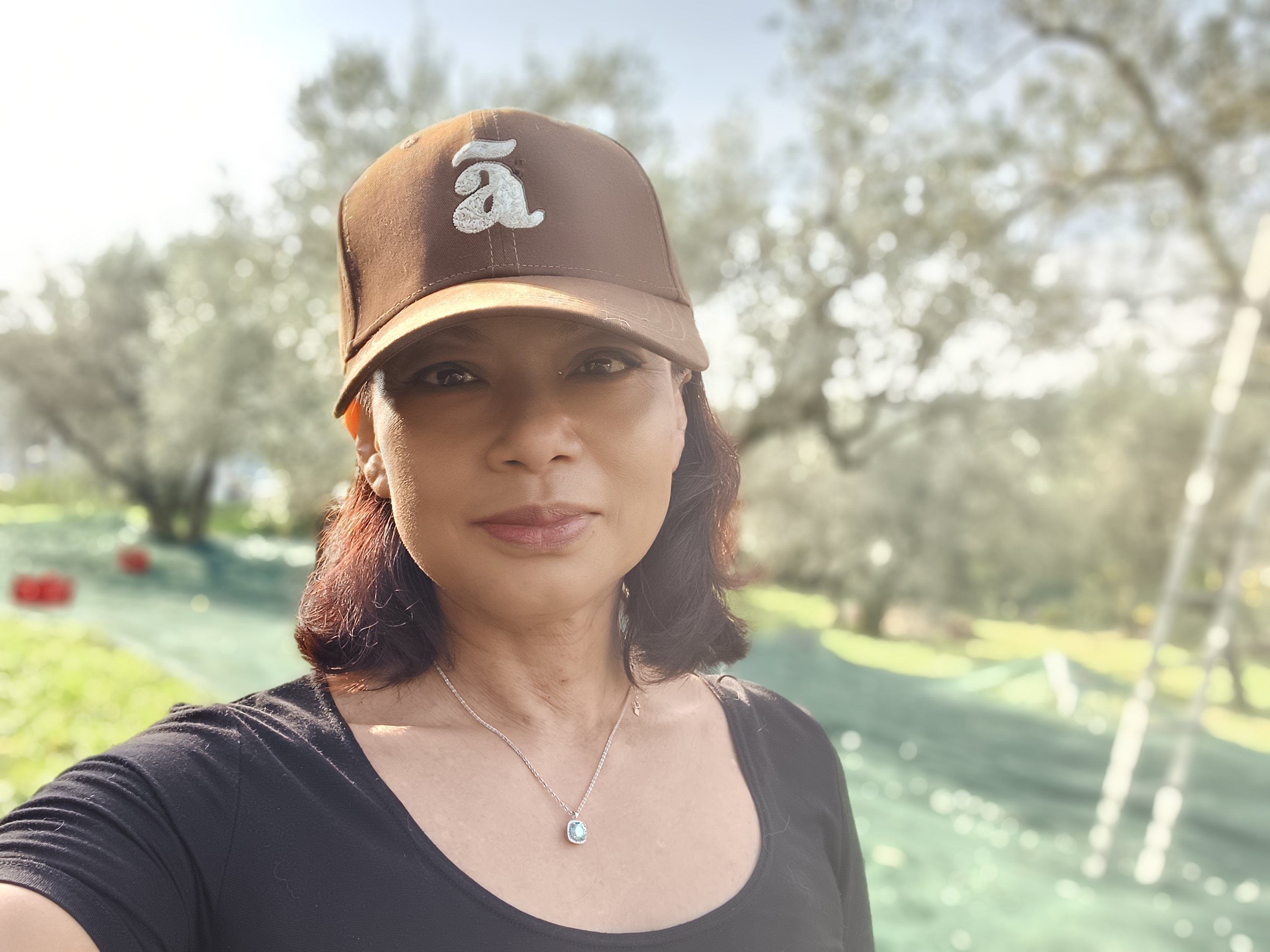 Portrait of Genevieve Cheung, founder of Genevieve Grove, in the Tuscan countryside surrounded by olive trees. Ritratto di Genevieve Cheung, fondatrice di Genevieve Grove, nella campagna toscana circondata da ulivi.