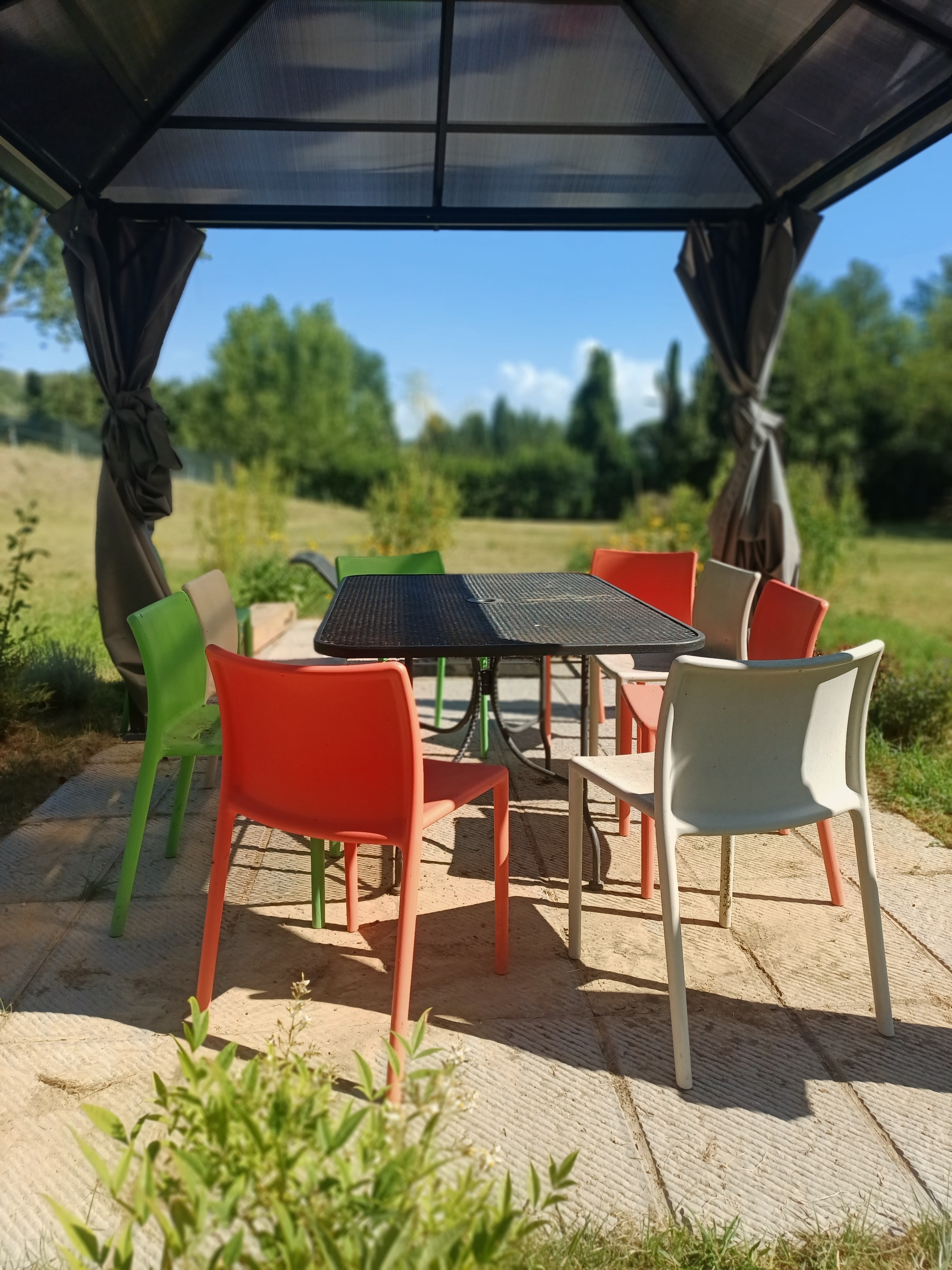Outdoor dining table and chairs beneath a gazebo overlooking the Tuscan countryside at Genevieve Grove